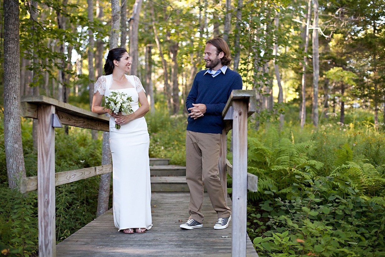 bride and groom smiling together on wooden bridge at wedding at the Inn at Ocean's Edge