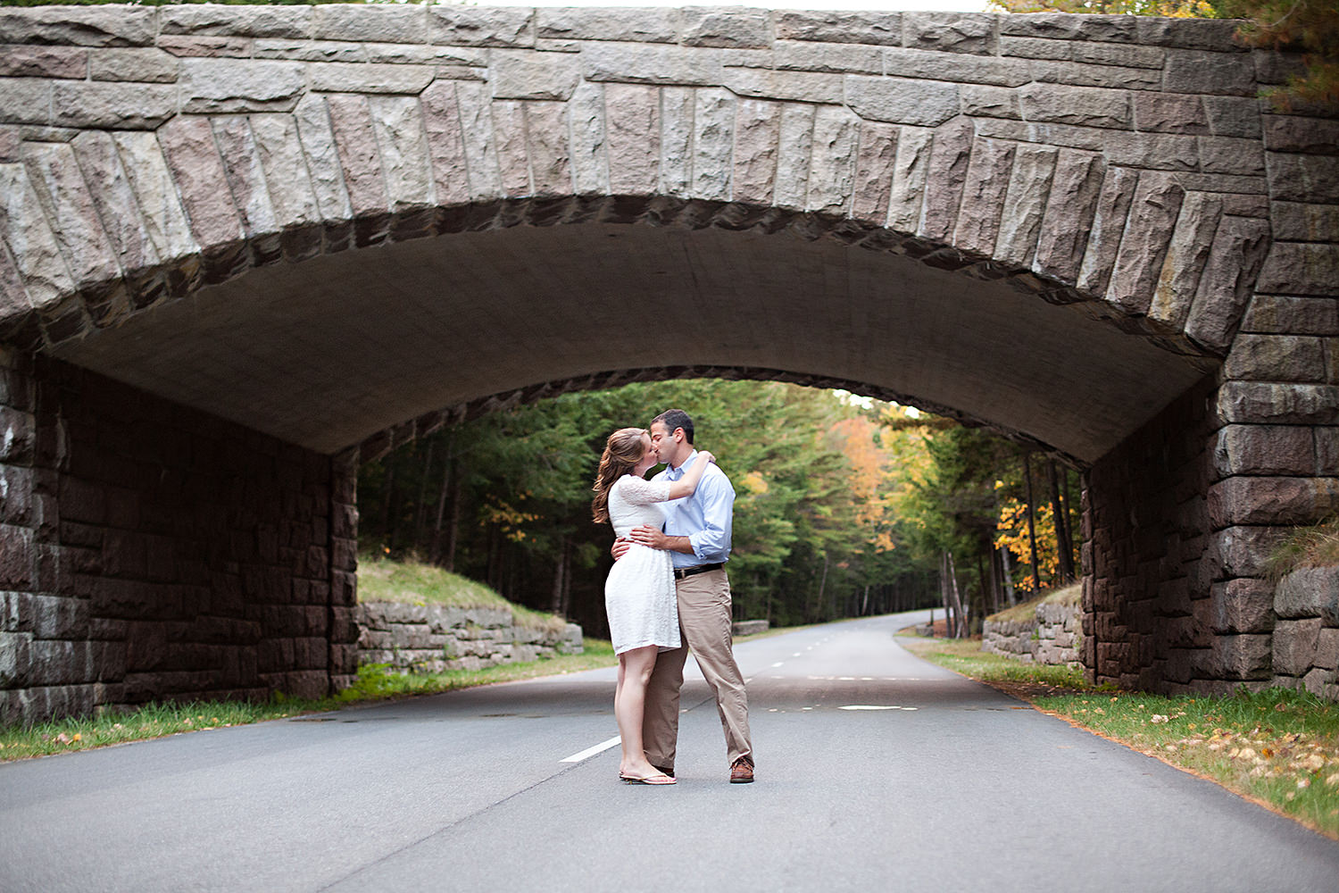 A couple kisses under a bridge in Acadia National Park