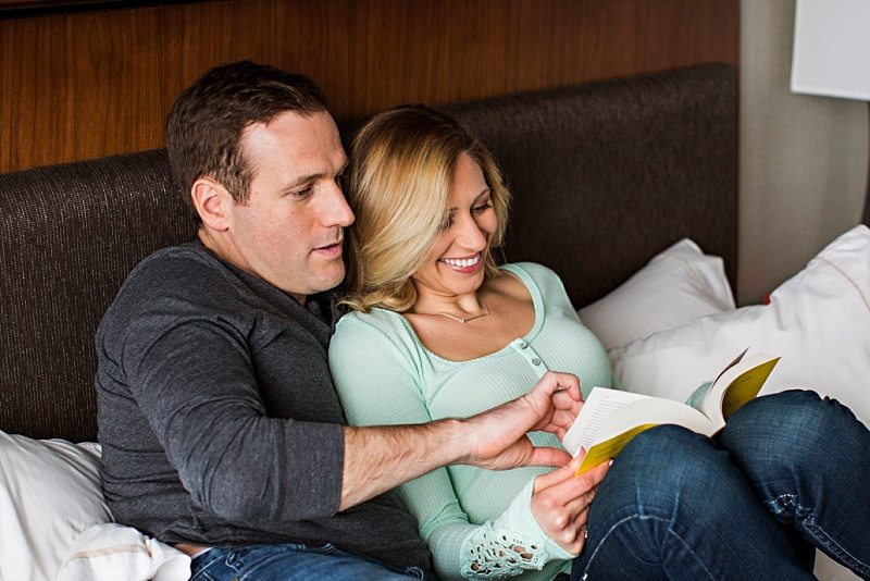 Engaged couple reading together in hotel room during Portland, Maine engagement photos