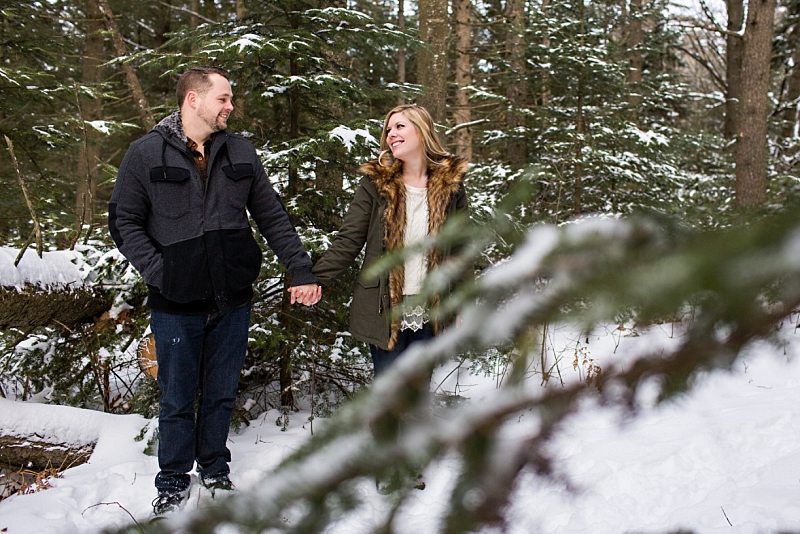 A couple holds hands in the snowy woods of Freeport, Maine.