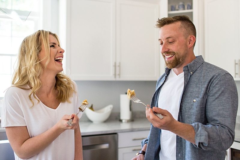 A lifestyle photo of a couple laughing and eating pancakes together in their kitchen.