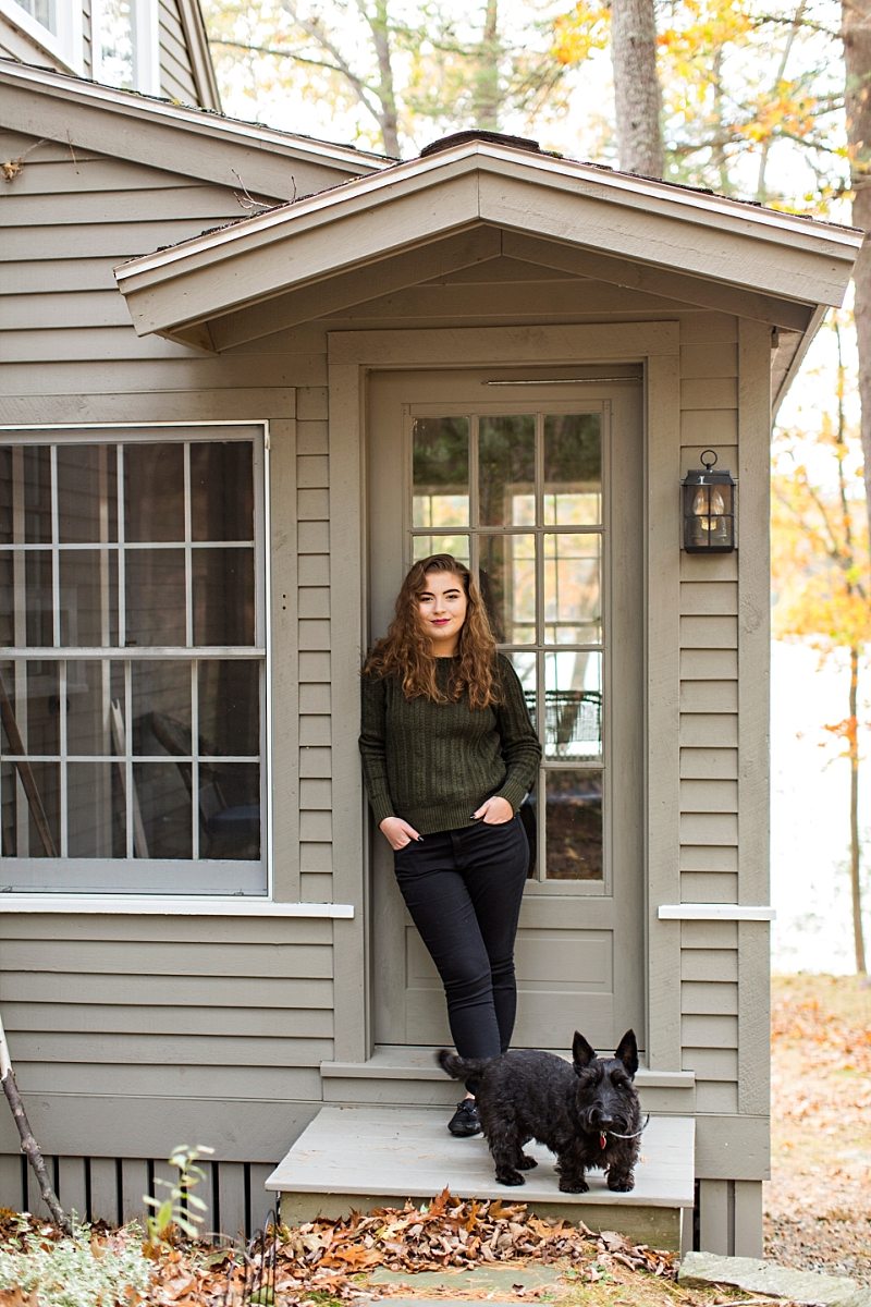 A girl poses against a door with her Scottie dog for her senior portraits.