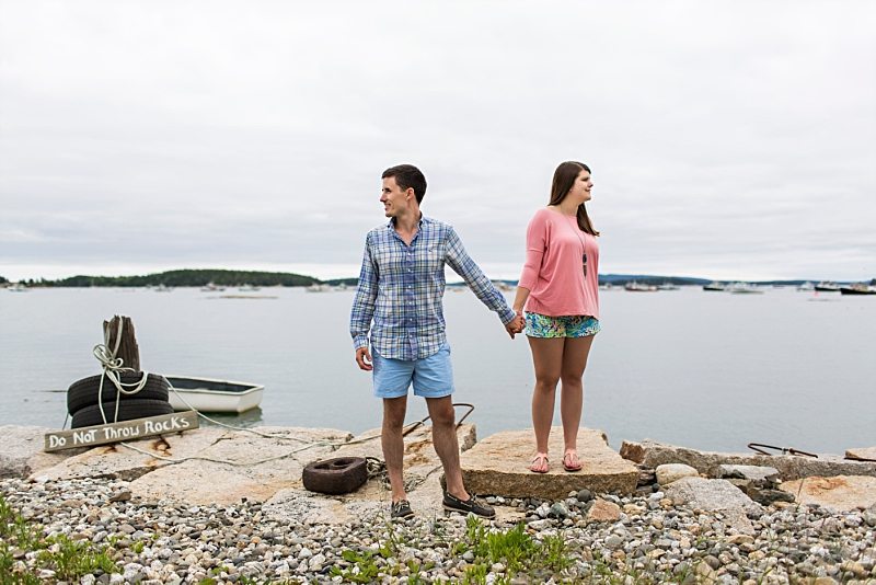 A couple holds hands at water's edge in Stonington, Maine.