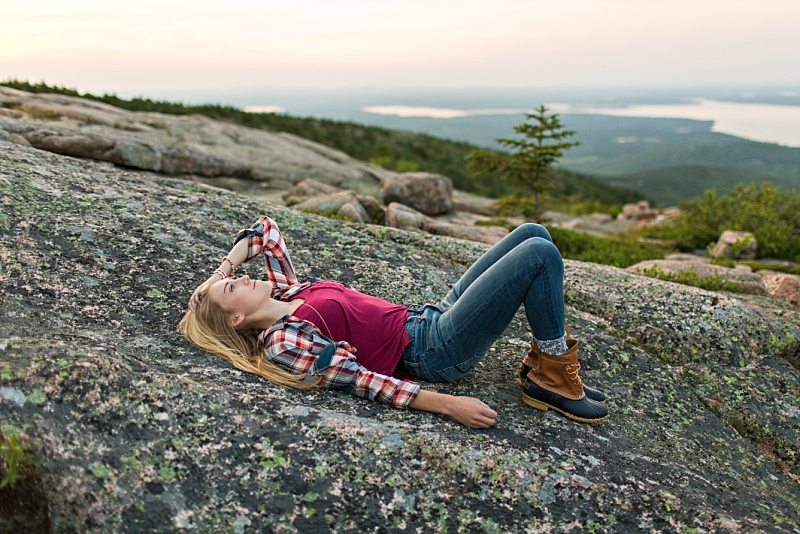 A girl lies on Cadillac Mountain for her senior portraits.