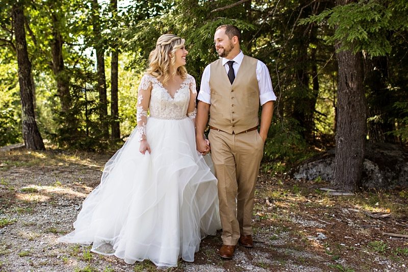 A bride and groom hold hands and smile at each other in Norway, Maine.