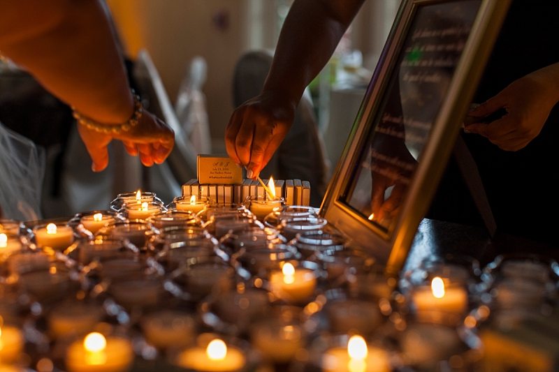 Hands light candles in memory of family members who couldn't make it to the wedding.