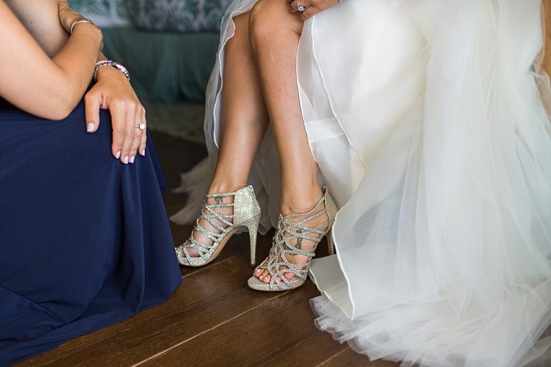 A close up of a bride's shoes that her sister has just places on her feet.