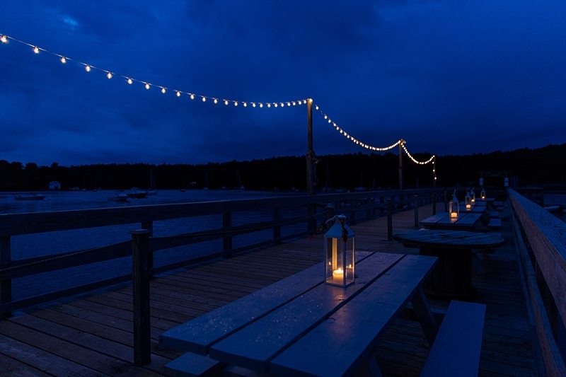 Twilight creates dark blue skies in this photo of lanterns and bistro lights lighting the outside of The Contented Sole in Maine.