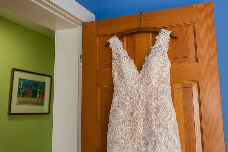 A wedding dress hangs on a door with bright blue and green walls around it.