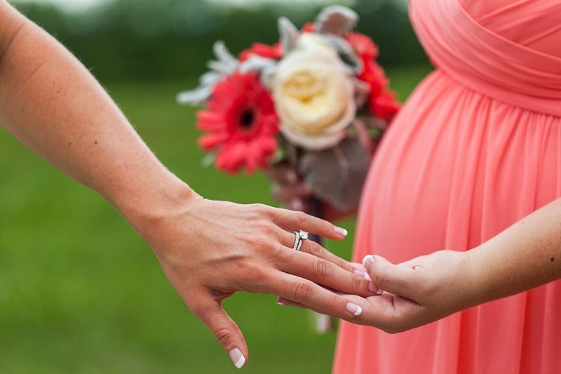 A close up of the bride's hands as she shows her new wedding ring to a bridesmaid.