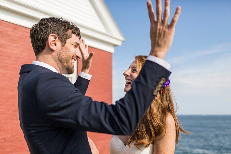 A groom raises his hands in the air in excitement as he looks at the bride.