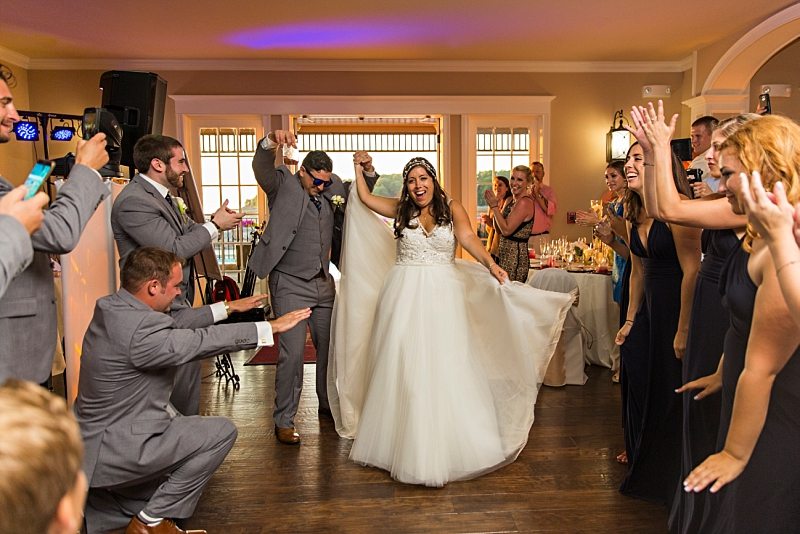 A wedding party cheers as the bride and groom dance their way into the reception.