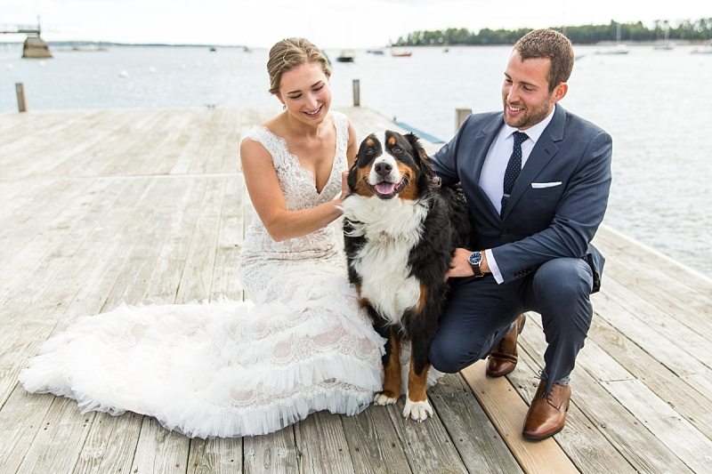 A bride and groom kneel with their dog for a portrait on the dock in Northeast Harbor, Maine.