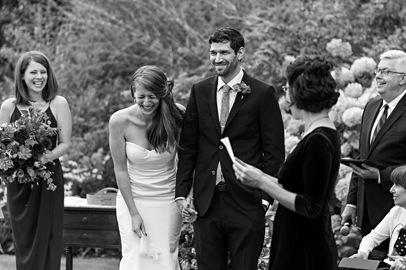 A bride and groom laugh during one of the readings during their wedding ceremony.