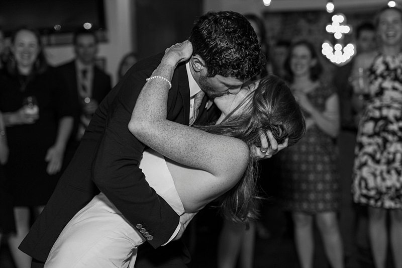 A groom dips his bride and kisses her at the end of their first dance.