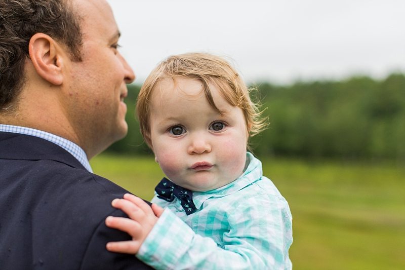 A baby focuses on the camera as his father carries him to the ceremony.