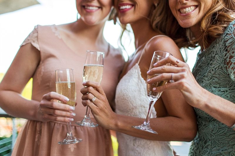 The bride and her friends smile while holding glasses of champagne.
