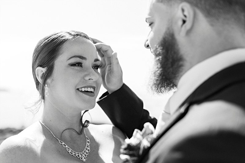 A bride smiles at the groom as he sweeps hair out of her eyes.