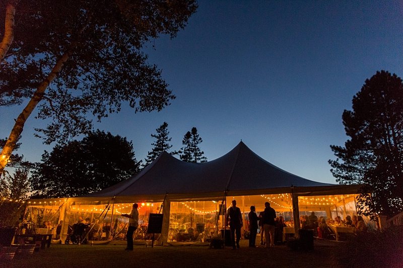 A wedding tent lit up at twilight.