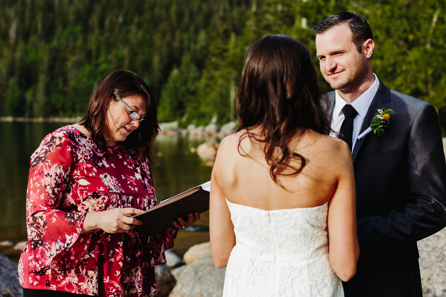 Groom smiling at bride during wedding ceremony in Acadia National Park
