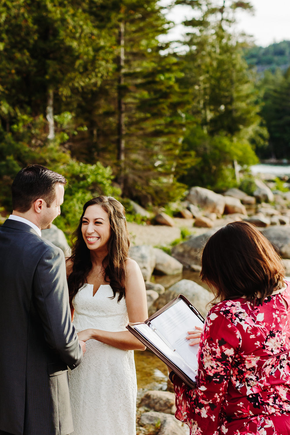 Bride smiles at groom during wedding ceremony at Jordan Pond in Acadia National Park