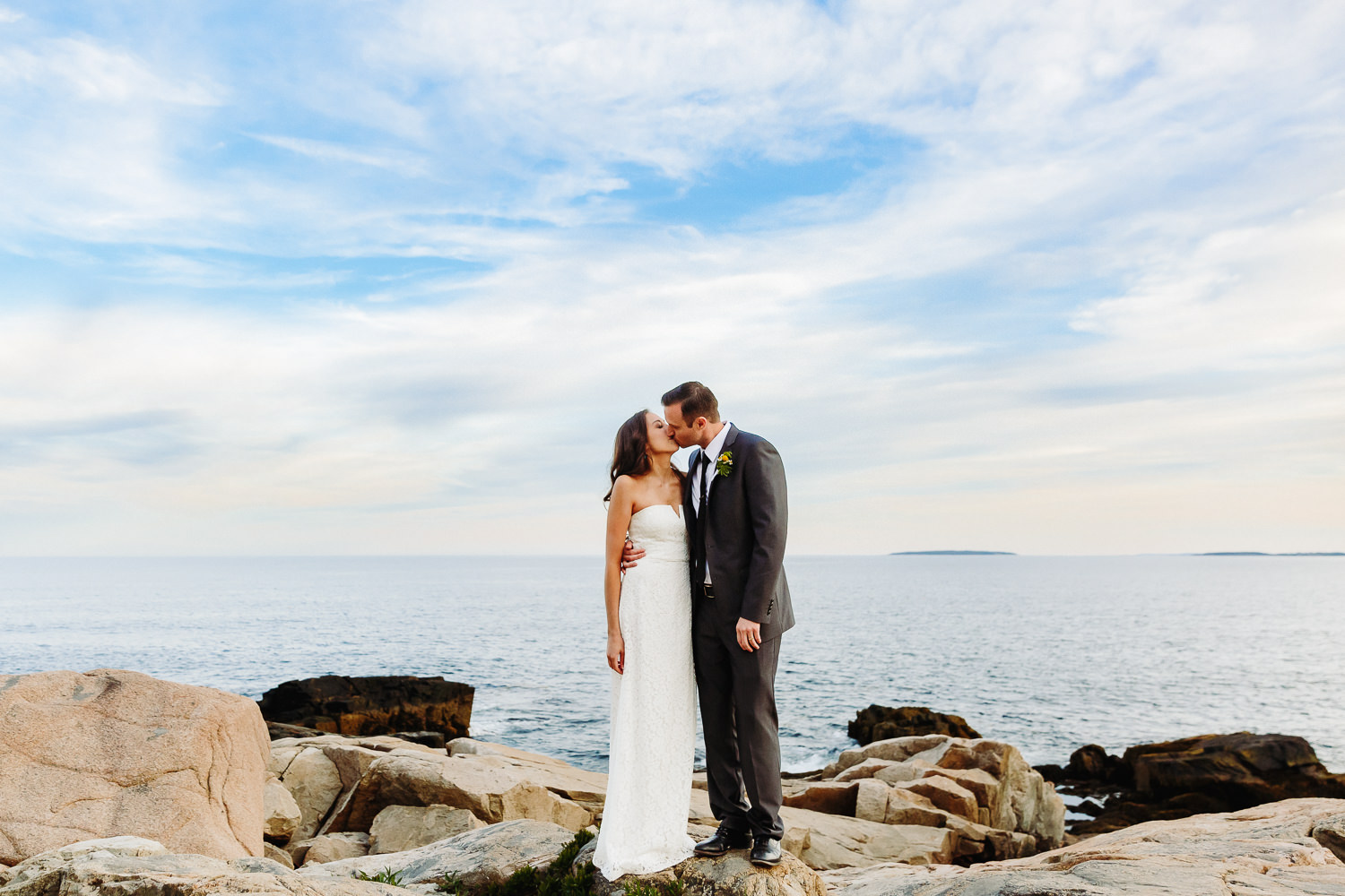 Bride and groom kissing on cliffs during elopement at Otter Point in Acadia National Park