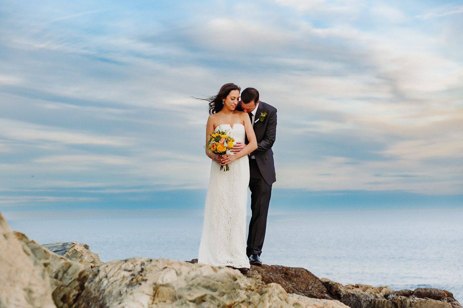 Bride and groom pose on cliffs at Otter Point in Acadia National Park.