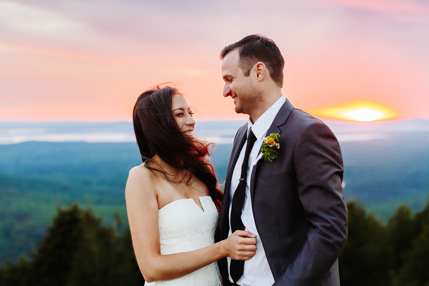 Bride and groom laughing in the wind on Cadillac Mountain at sunset