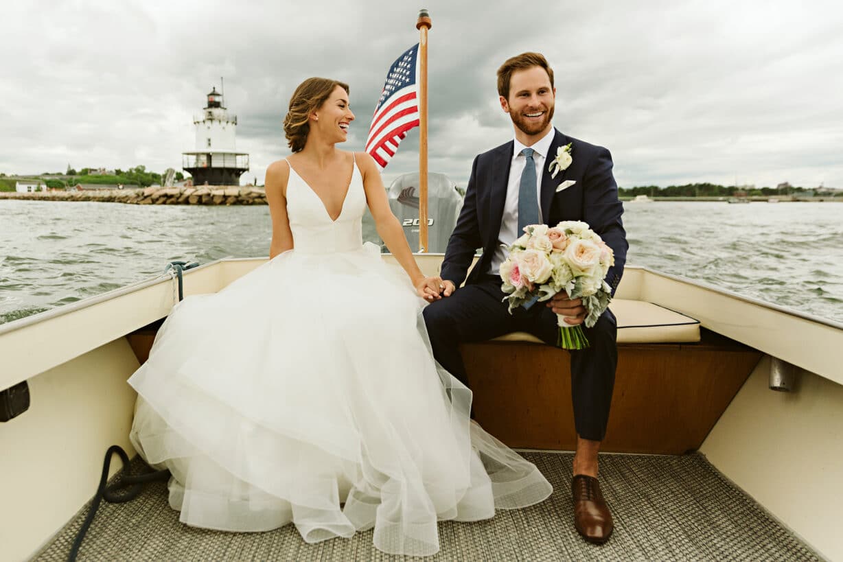Bride and groom on boat in front of lighthouse