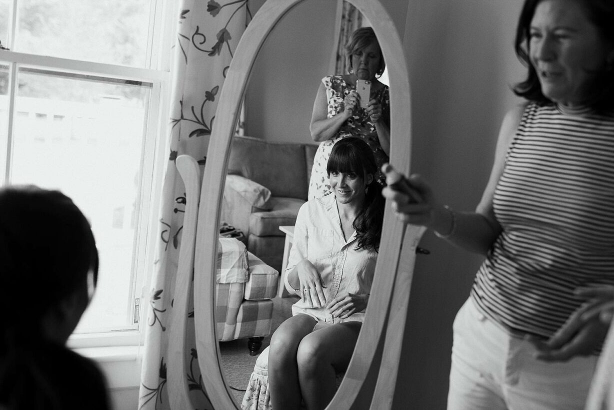 Bride smiling in mirror as she gets ready for her Bar Harbor wedding