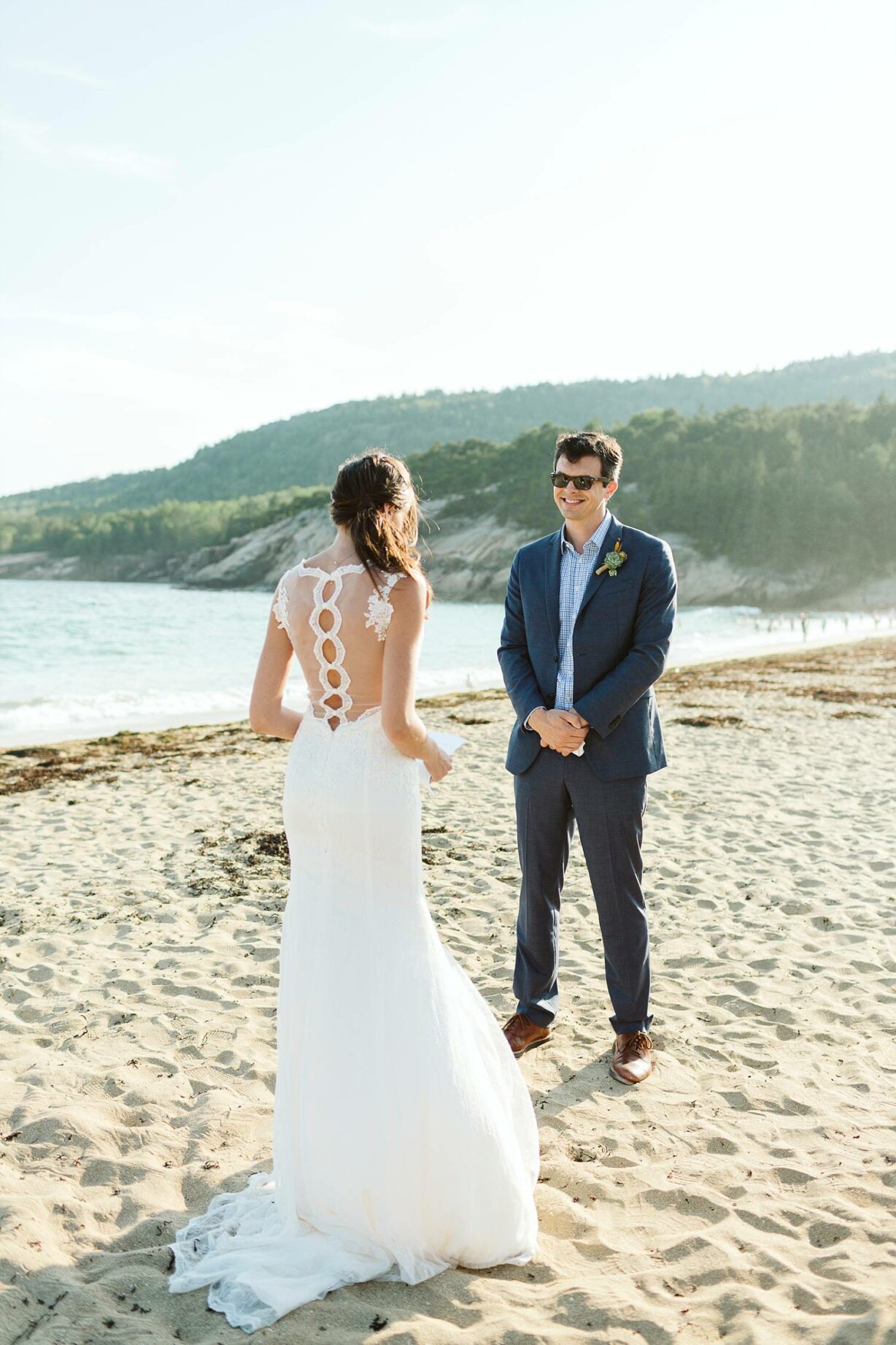 groom smiles as bride reads her vows at Sand Beach Acadia elopement