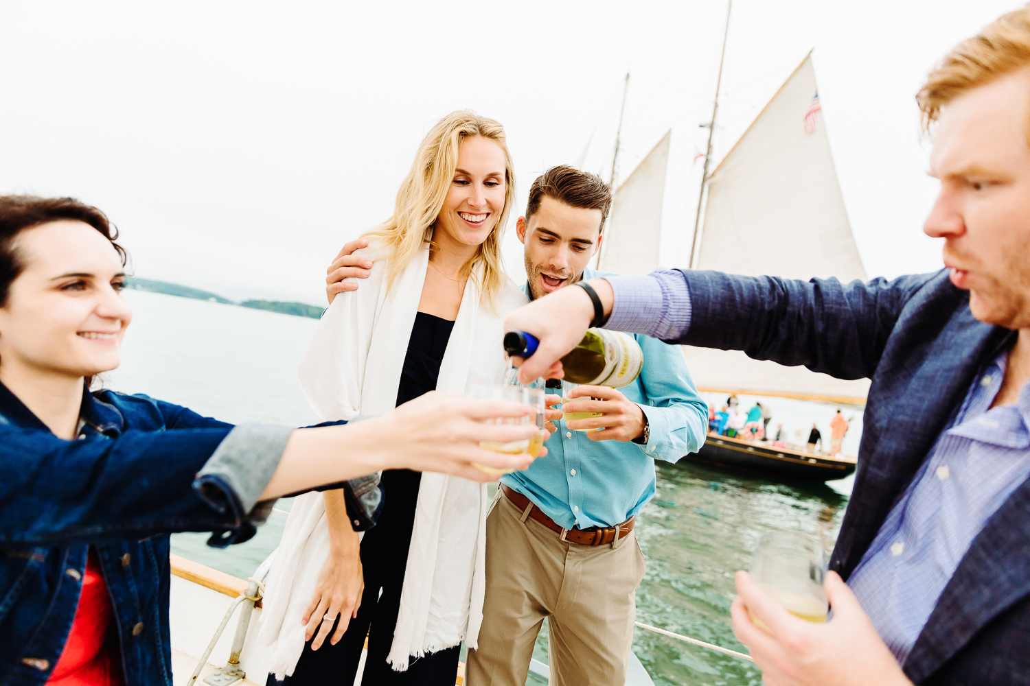 wedding guests pouring wine during Portland Maine rehearsal dinner cruise