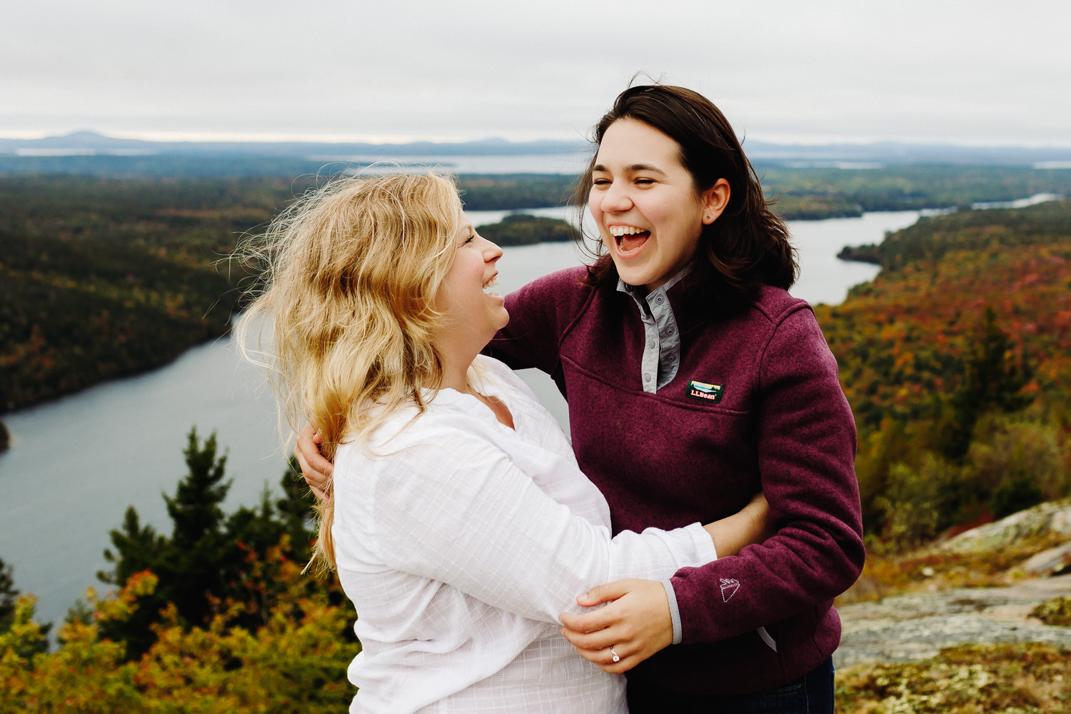 Two women laugh together after proposing to each other on Beech Mountain in Acadia National Park