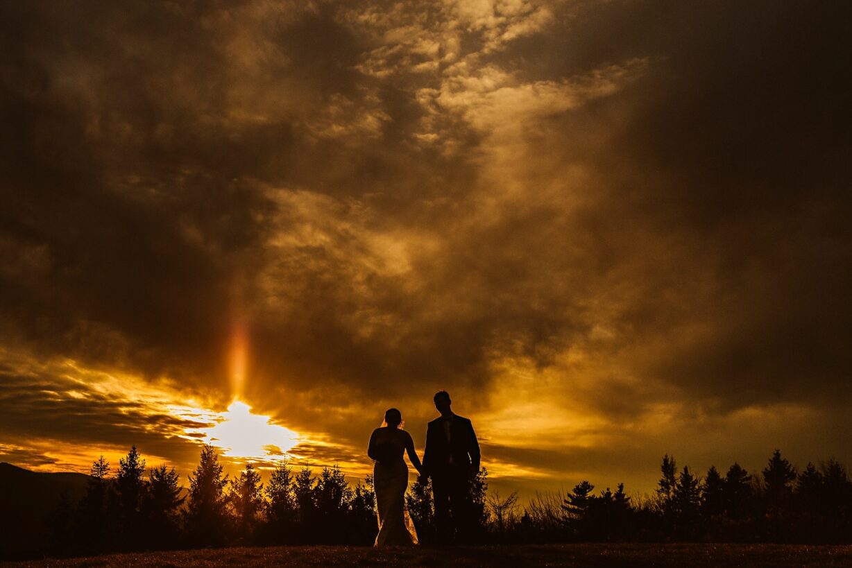 Silhouette of bride and groom walking at sunset