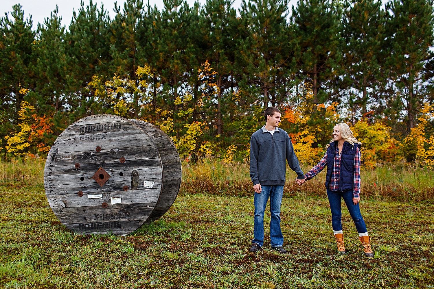 couple next to wheel during Fall engagement photos in Maine