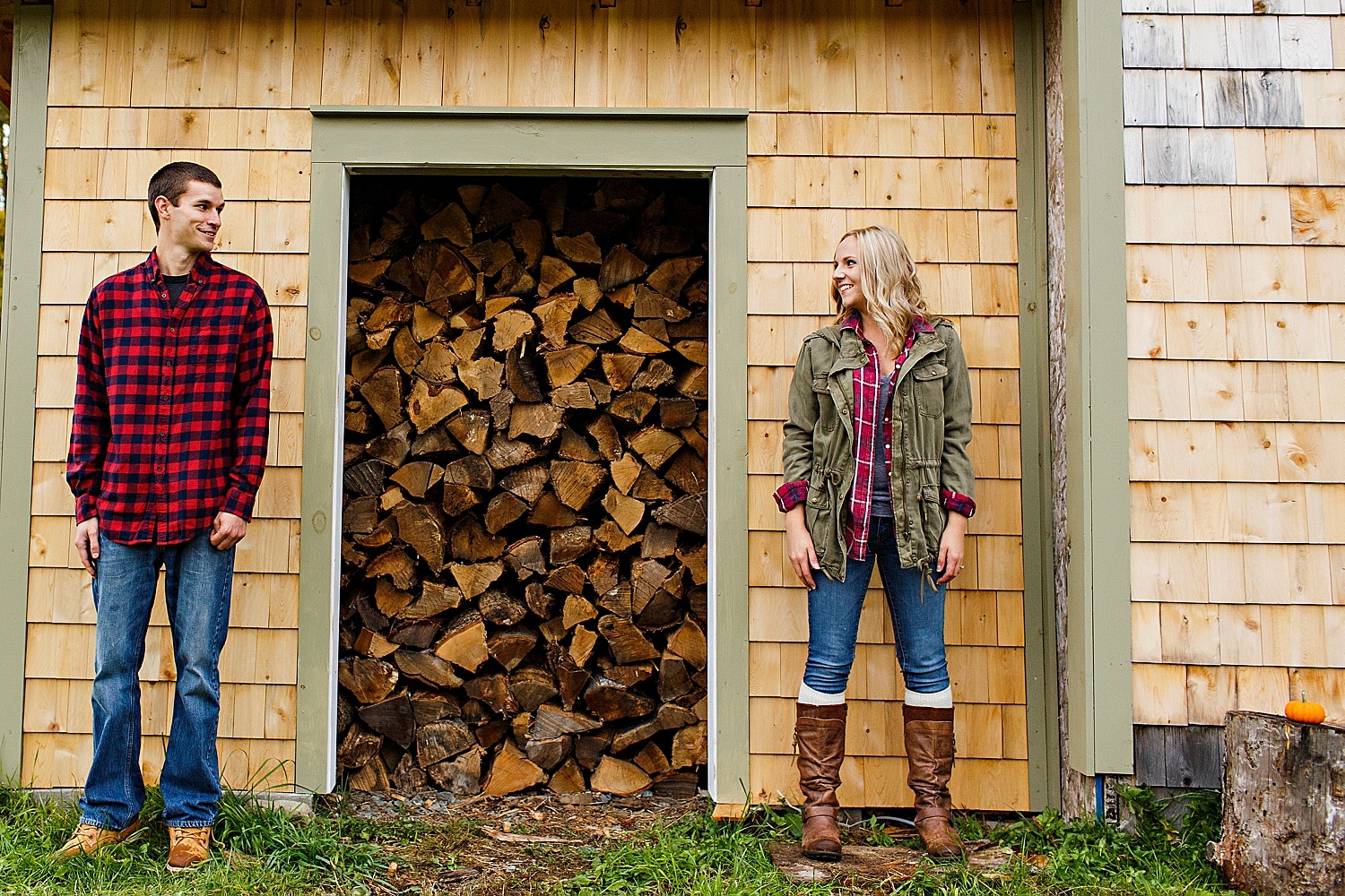 couple next to wood pile during Fall engagement photos in Maine
