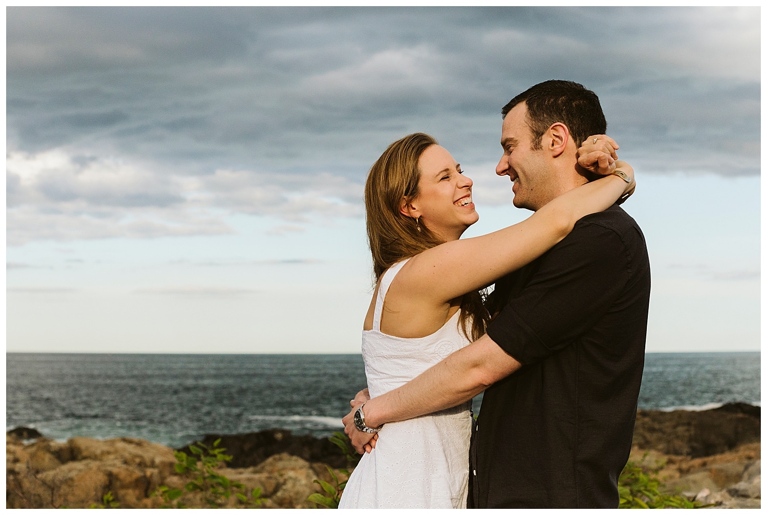 couple embracing in front of ocean during Ogunquit Maine engagement photos
