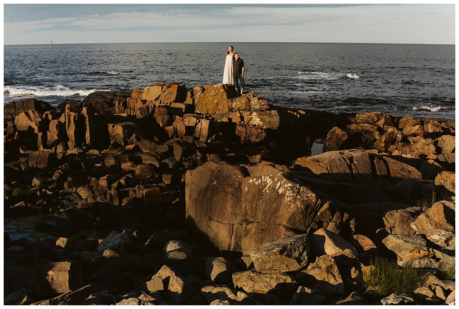 couple standing on oceanside cliffs at sunset