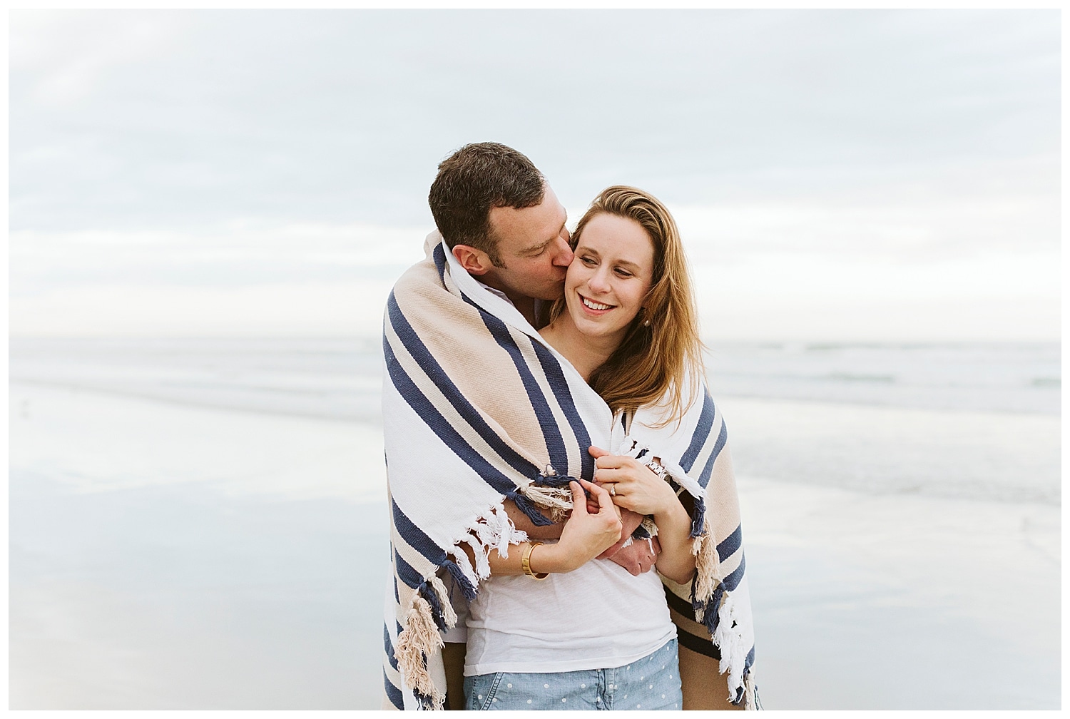 couple wrapped up in a blanket on the beach