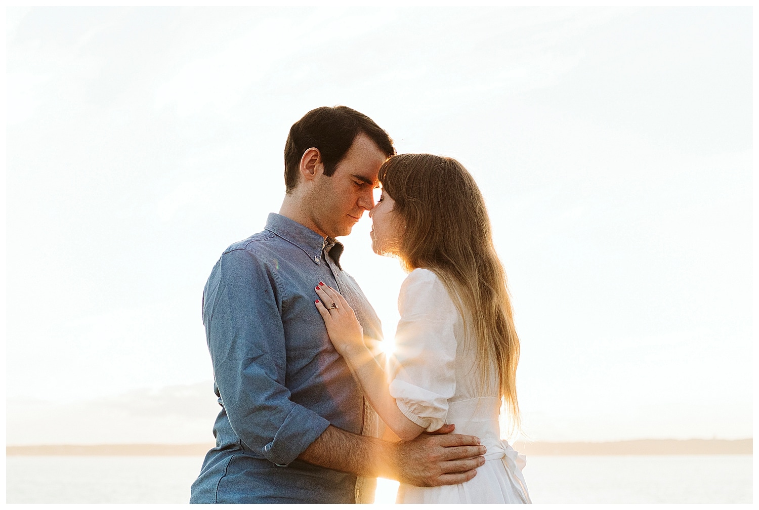 sunburst between couple during Engagement photos in Bristol Maine