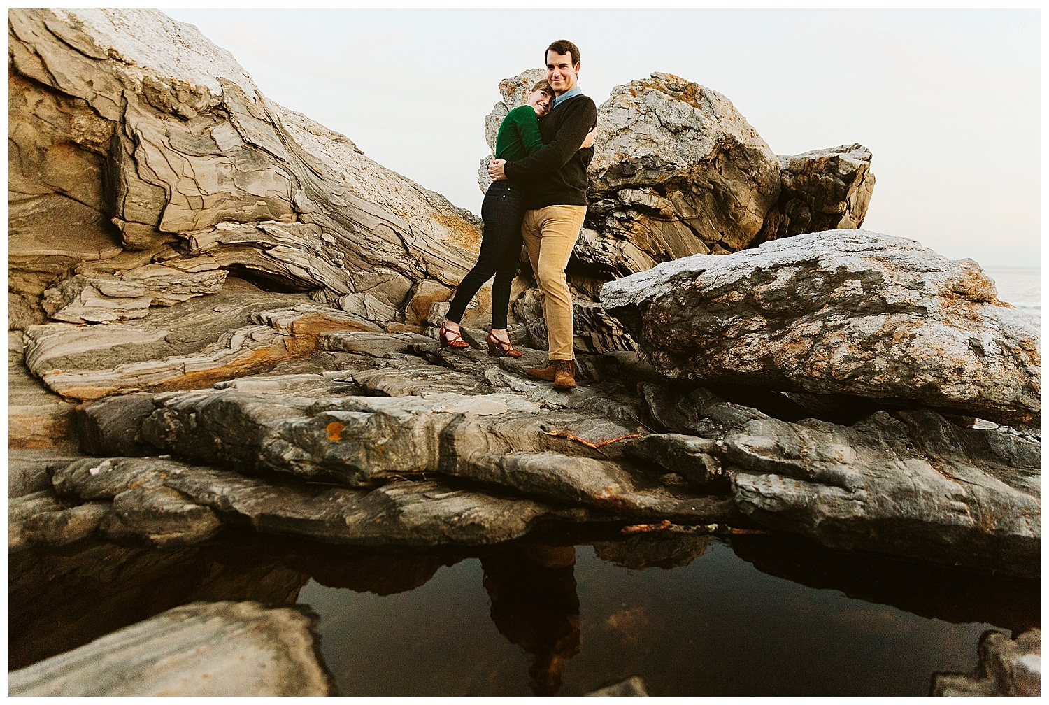 couple hugging on cliffs during Engagement photos in Bristol Maine