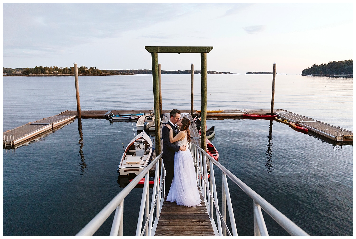 bride and groom kiss on dock at Boothbay Harbor wedding
