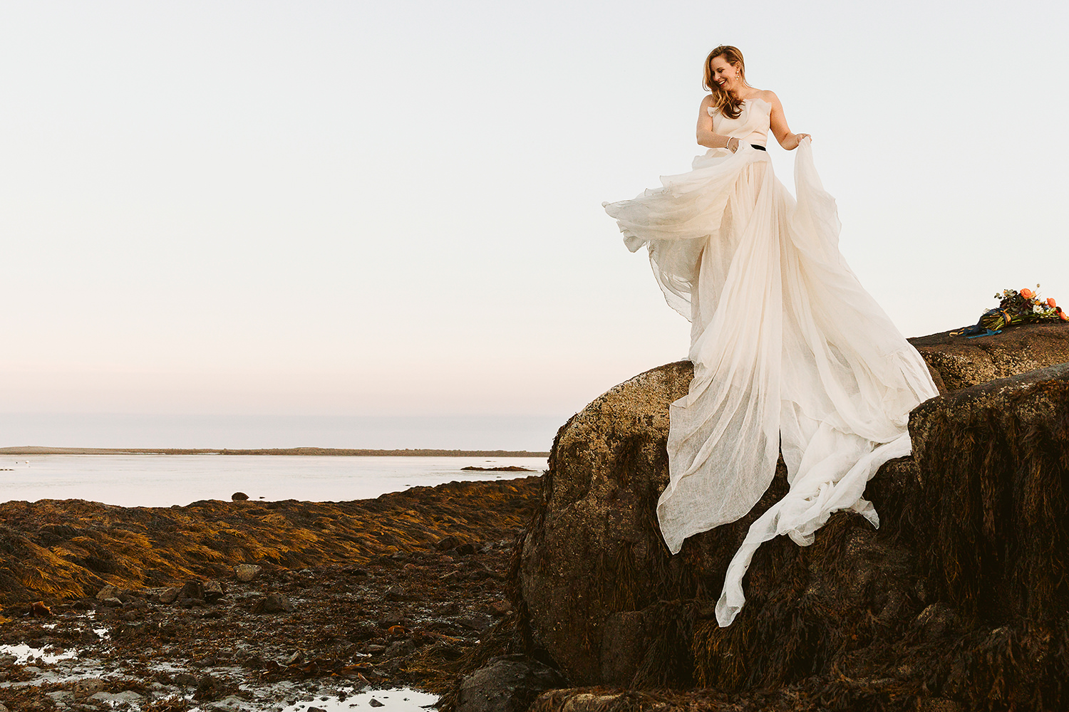 bride dancing on boulder on beach during  micro wedding in Kennebunkport Maine