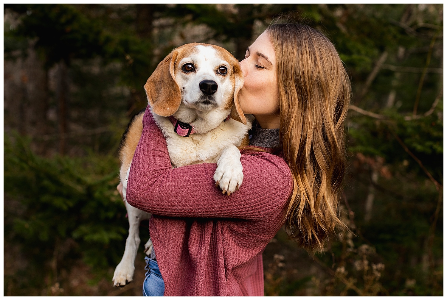 woman holding and kissing beagle