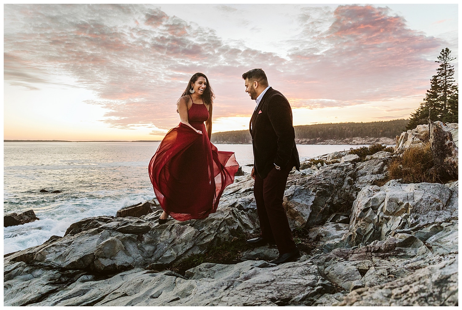 woman swishing her red dress while her fiance looks on in Acadia National Park