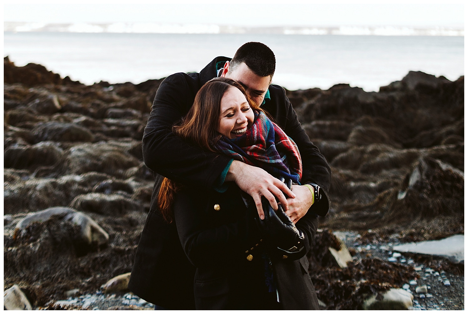 couple embracing during at Quoddy Head State Park during engagement photos in Lubec, Maine