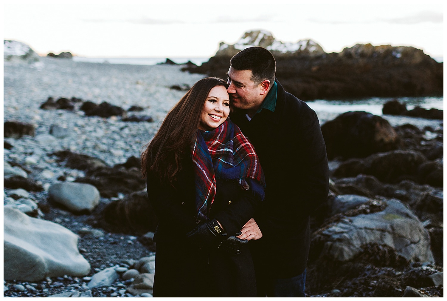 couple cuddling at Quoddy Head State Park during engagement photos in Lubec, Maine