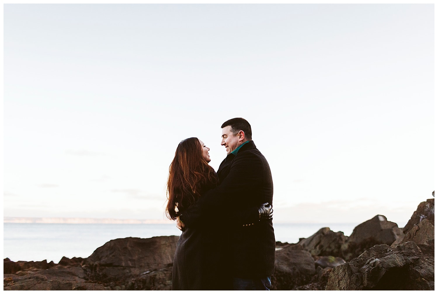 couple smiling at each other at Quoddy Head State Park during engagement photos in Lubec, Maine