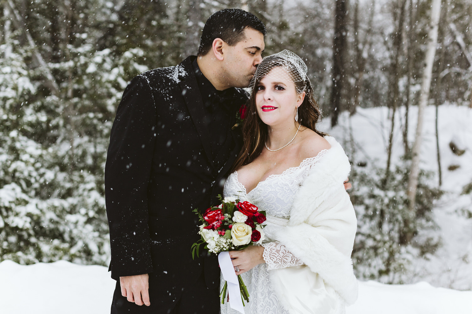 groom kisses bride's forehead during winter wedding in Millinocket Maine