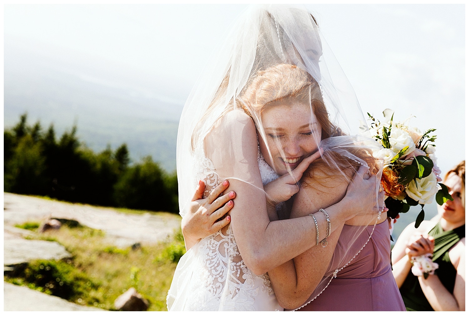 bride and sister hug on Cadillac Mountain in Acadia National Park